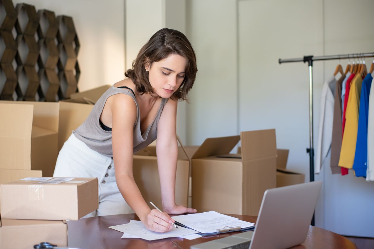 A small business owner reviewing paperwork surrounded by moving boxes.