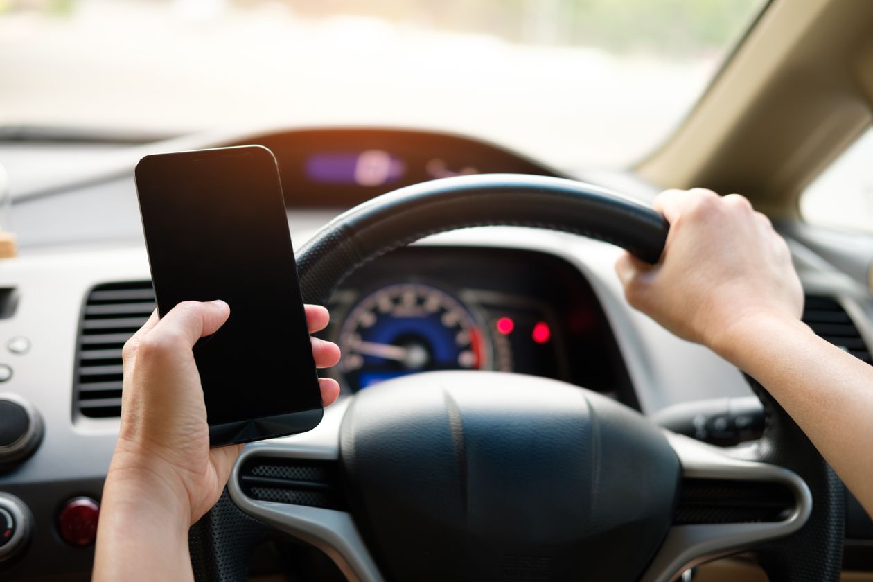 A driver holding a phone while behind the wheel of a car.