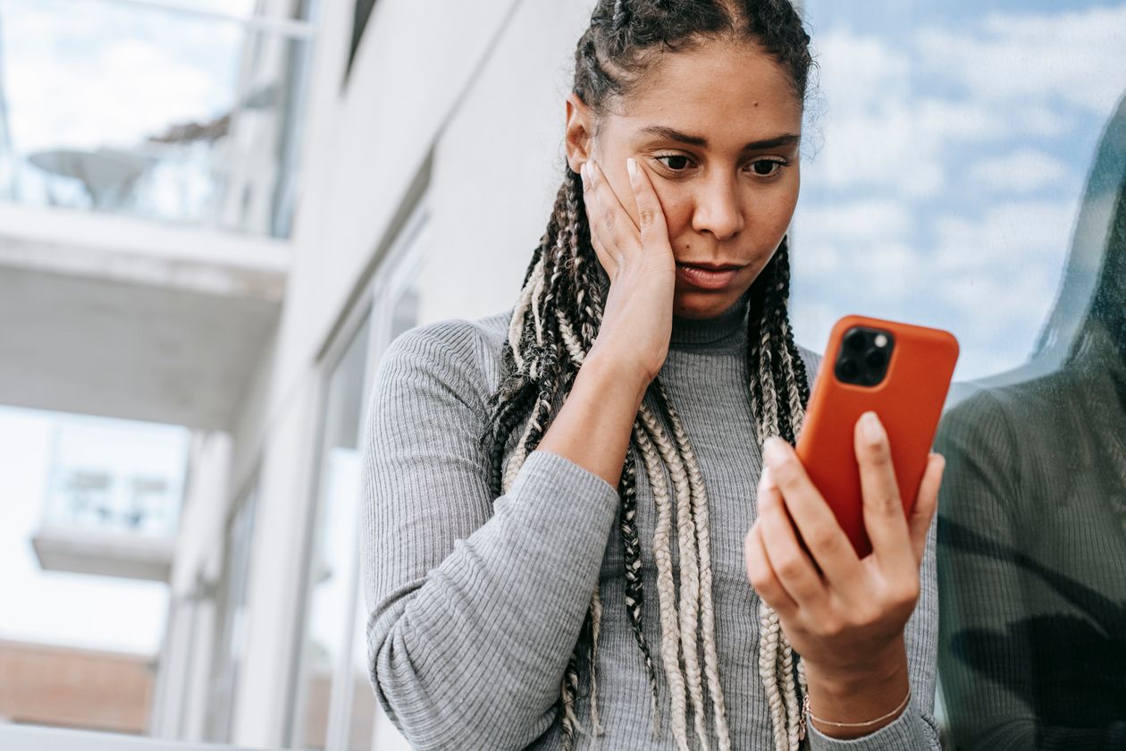 A woman looking at her phone with a concerned expression.