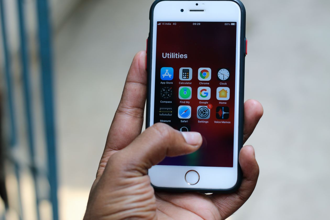 A hand holding a smartphone showing its home screen.