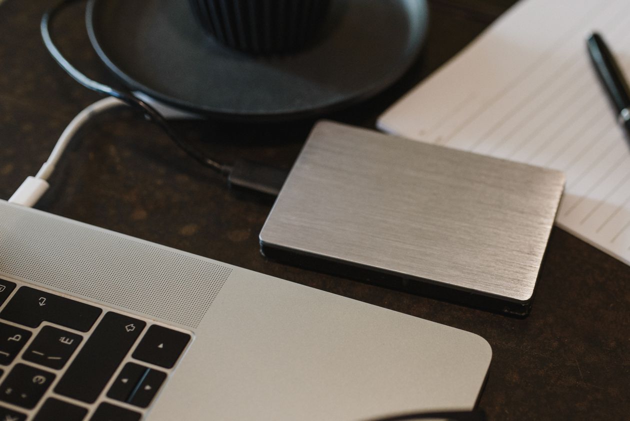 An external hard drive sitting on a desk beside a laptop.