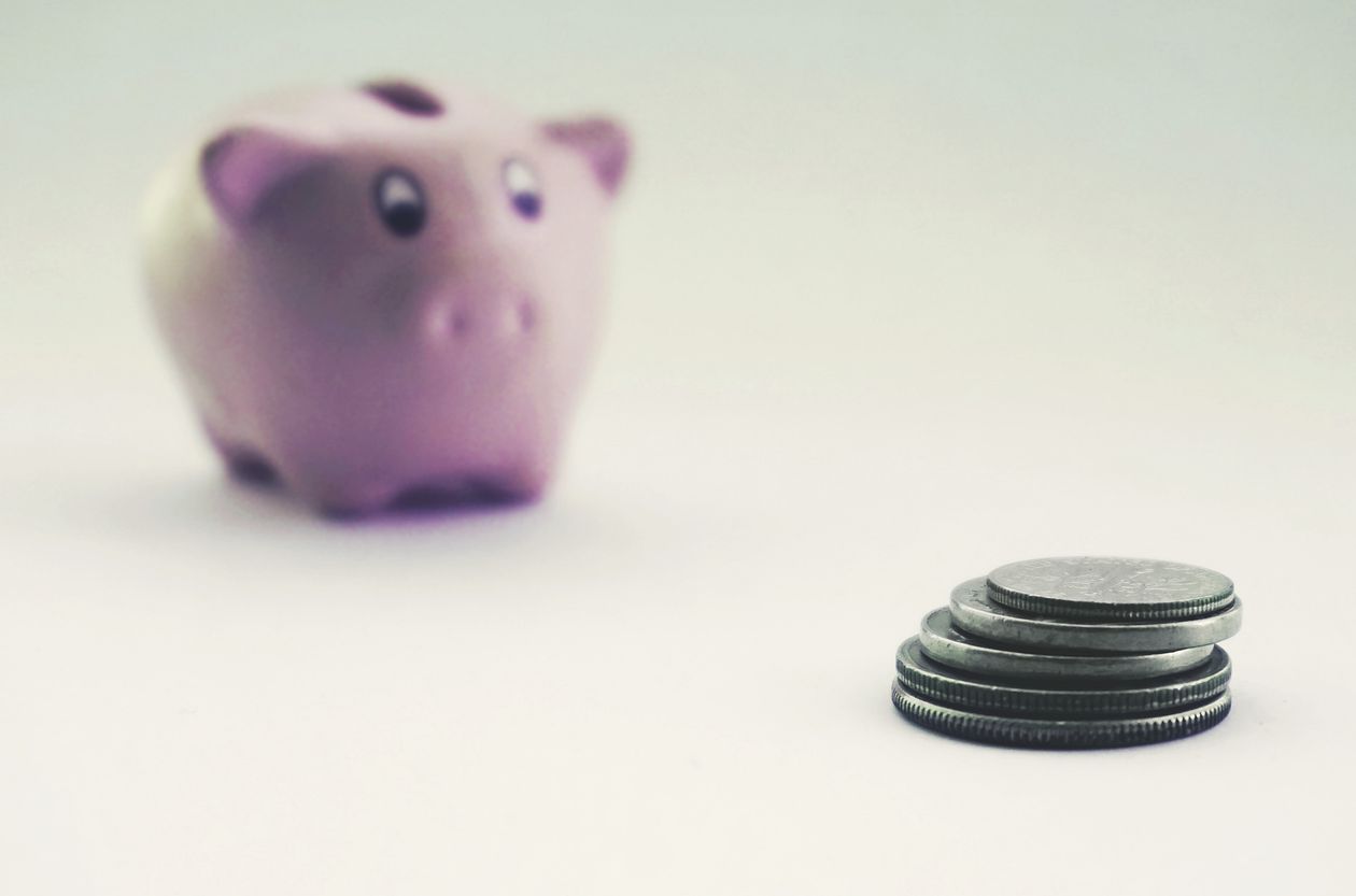 A piggy bank beside a small stack of coins.