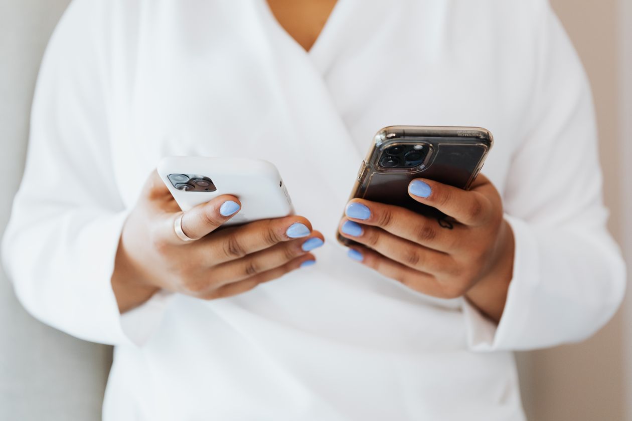 Two hands holding two smartphones.