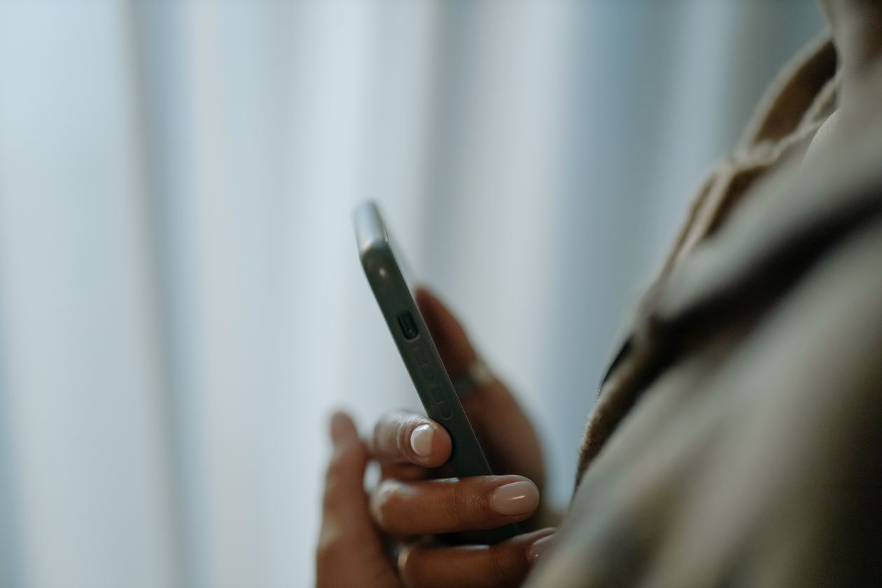 A hand holding a smartphone from behind, viewed over the shoulder.